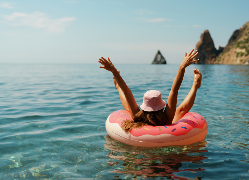 Woman in pink donut tube floating on a sunny lake